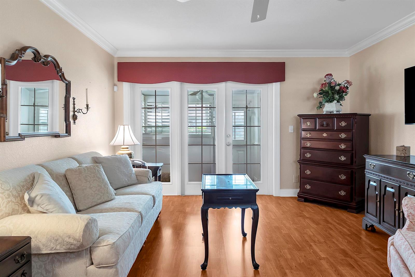 A living room features a light-colored sofa, a dark wood chest, and glass-paned French doors — 2930 Crosley Drive E # M, West Palm Beach FL 33415, WEST PALM BEACH, FL