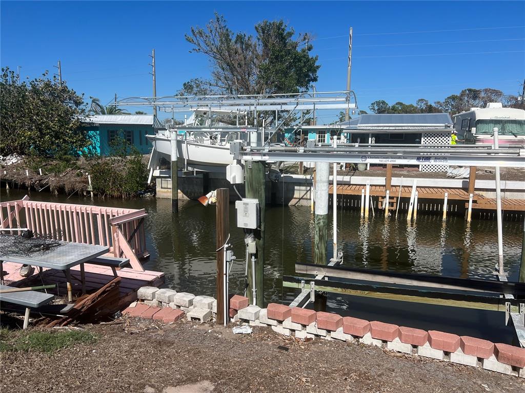 A boat lift holds a white boat over a canal next to a pink deck — 2061 S PINE ST, ENGLEWOOD, FL