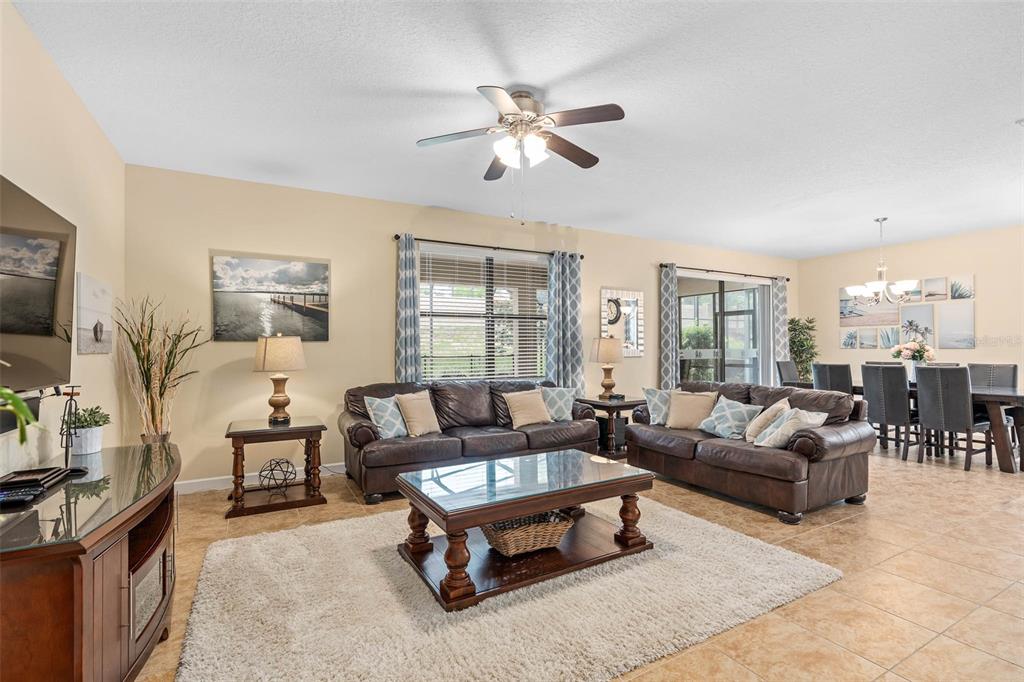 A living room with brown leather sofas, a glass coffee table, and a dining area — 1476 MOON VALLEY DRIVE, DAVENPORT, FL