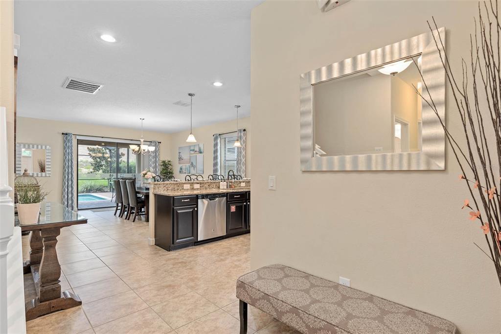A view from a hallway into an open-concept kitchen and dining area with tile flooring — 1476 MOON VALLEY DRIVE, DAVENPORT, FL