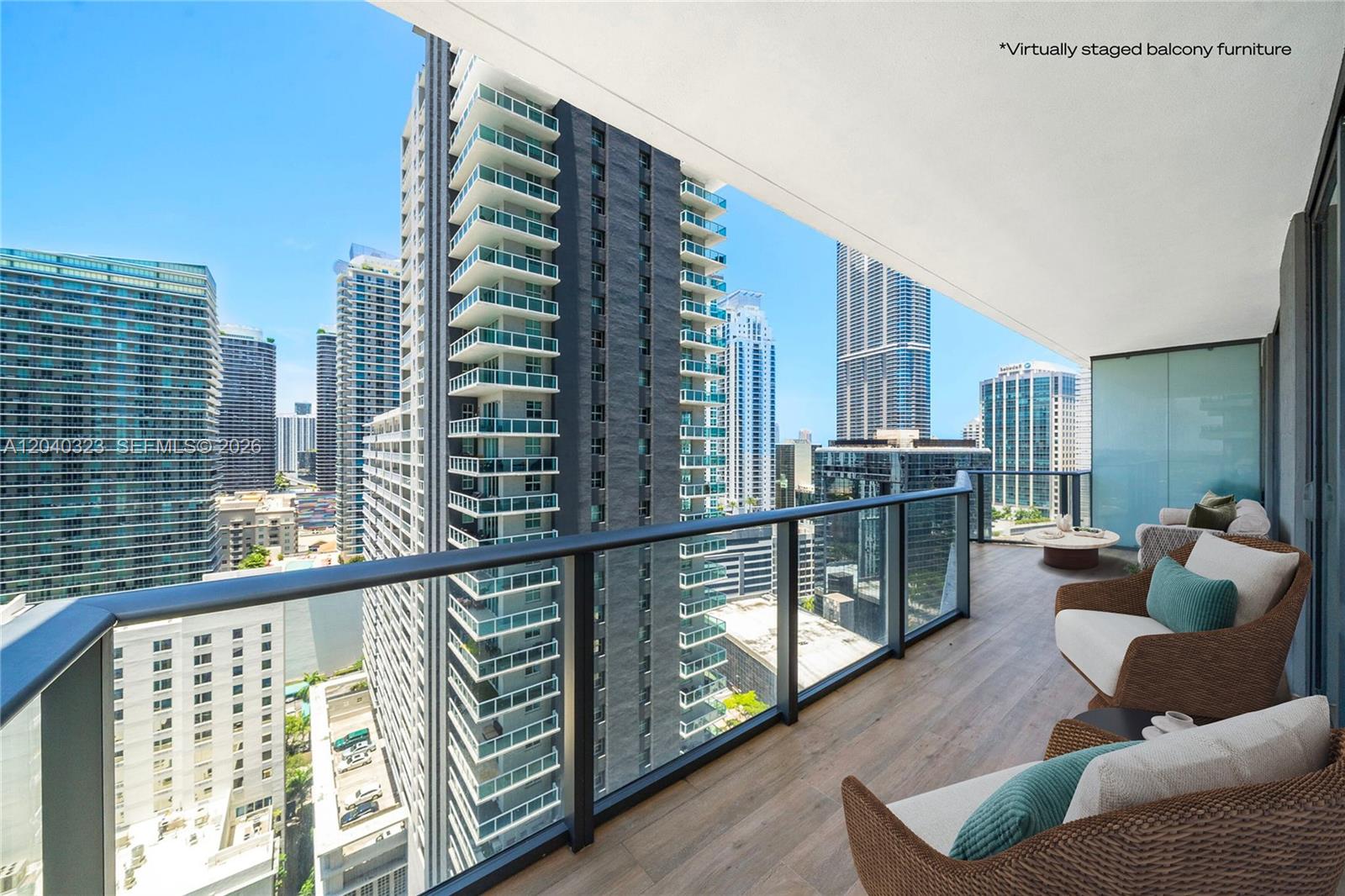 A high-rise balcony with wood-look flooring, glass railings, and a view of surrounding city skyscrapers — 1300 S Miami Ave # 2110, Miami FL 33130, MIAMI, FL