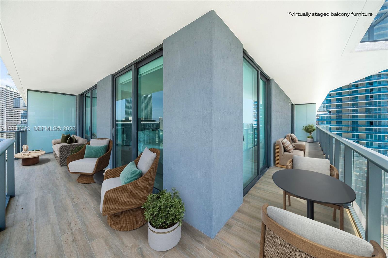 This balcony features wood-look tile flooring, glass railings, and virtually staged outdoor furniture — 1300 S Miami Ave # 2110, Miami FL 33130, MIAMI, FL