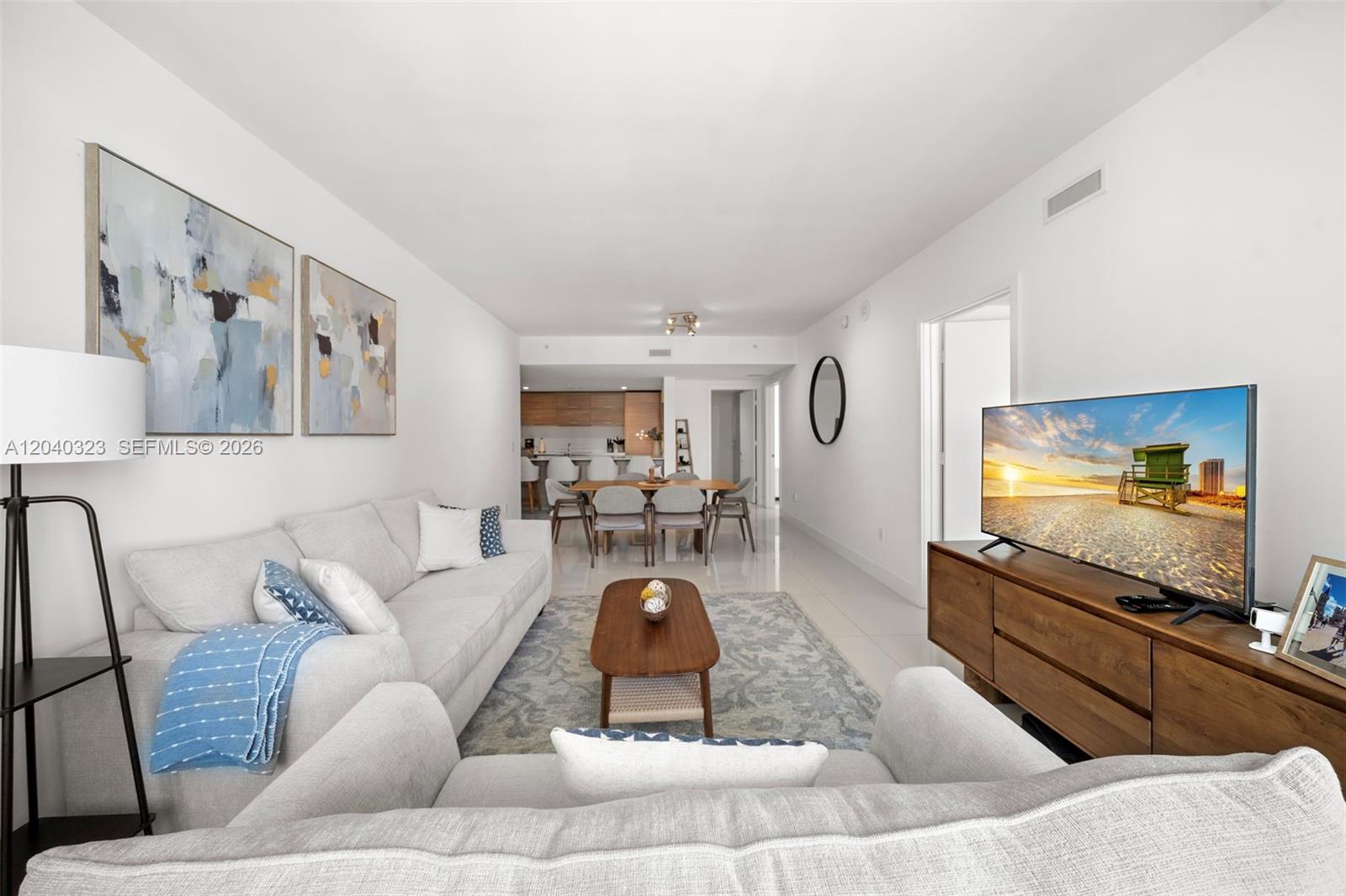 A living room features a light gray sofa, a wooden media console, and a dining area — 1300 S Miami Ave # 2110, Miami FL 33130, MIAMI, FL