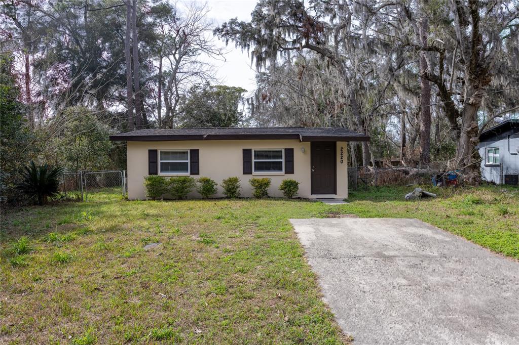A single-story house with a flat roof, beige exterior, and a concrete driveway — 2220 SE 46TH TERRACE, GAINESVILLE, FL