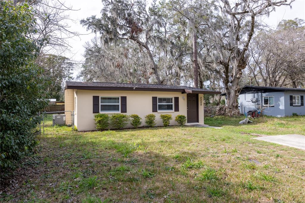 A single-story house with a tan exterior, dark shutters, and a brown front door — 2220 SE 46TH TERRACE, GAINESVILLE, FL