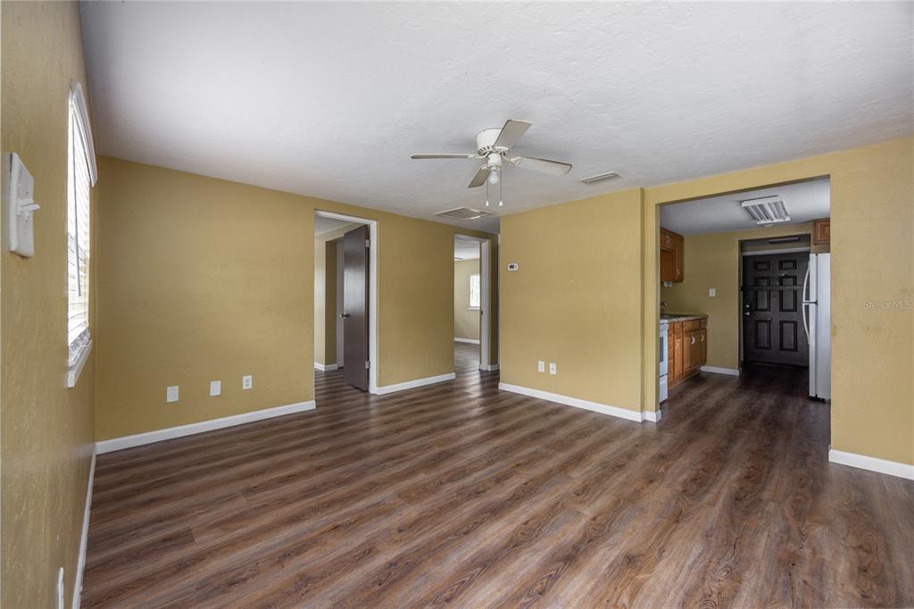 A living room with mustard yellow walls, wood-look flooring, and an adjacent kitchen area — 2220 SE 46TH TERRACE, GAINESVILLE, FL