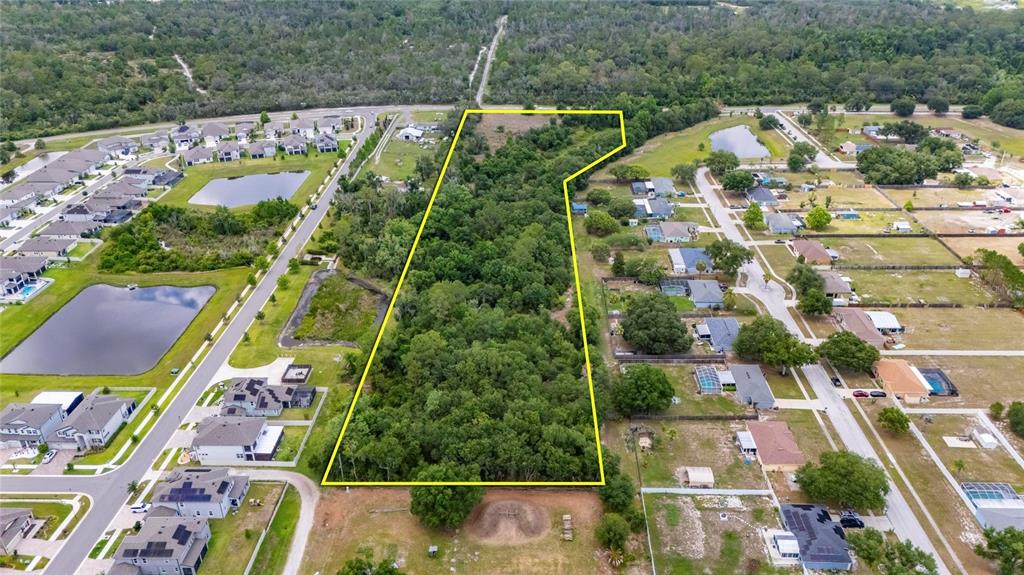 An aerial view shows a large, wooded rectangular lot outlined in yellow between residential neighborhoods — 13311 RHODINE ROAD, RIVERVIEW, FL