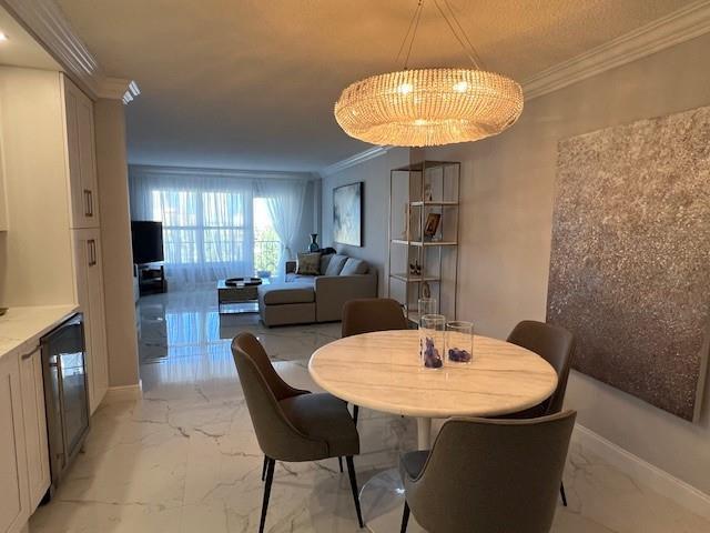 A dining area with a round marble table and chandelier opens into a living room — 405 N Ocean Boulevard # 825, Pompano Beach FL 33062, POMPANO BEACH, FL