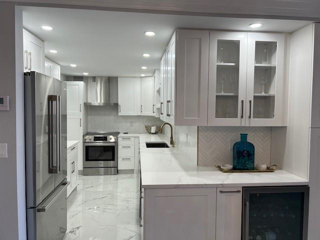 A modern kitchen features white cabinetry, marble-style countertops, stainless steel appliances, and light-colored tile flooring — 405 N Ocean Boulevard # 825, Pompano Beach FL 33062, POMPANO BEACH, FL