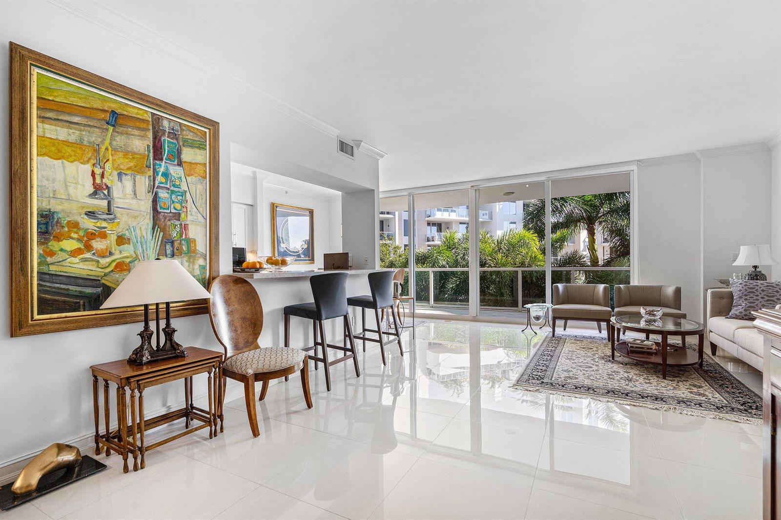 A bright living room features white tile floors, a breakfast bar, and large sliding glass doors — 500 SE Mizner Boulevard # A310, Boca Raton FL 33432, BOCA RATON, FL