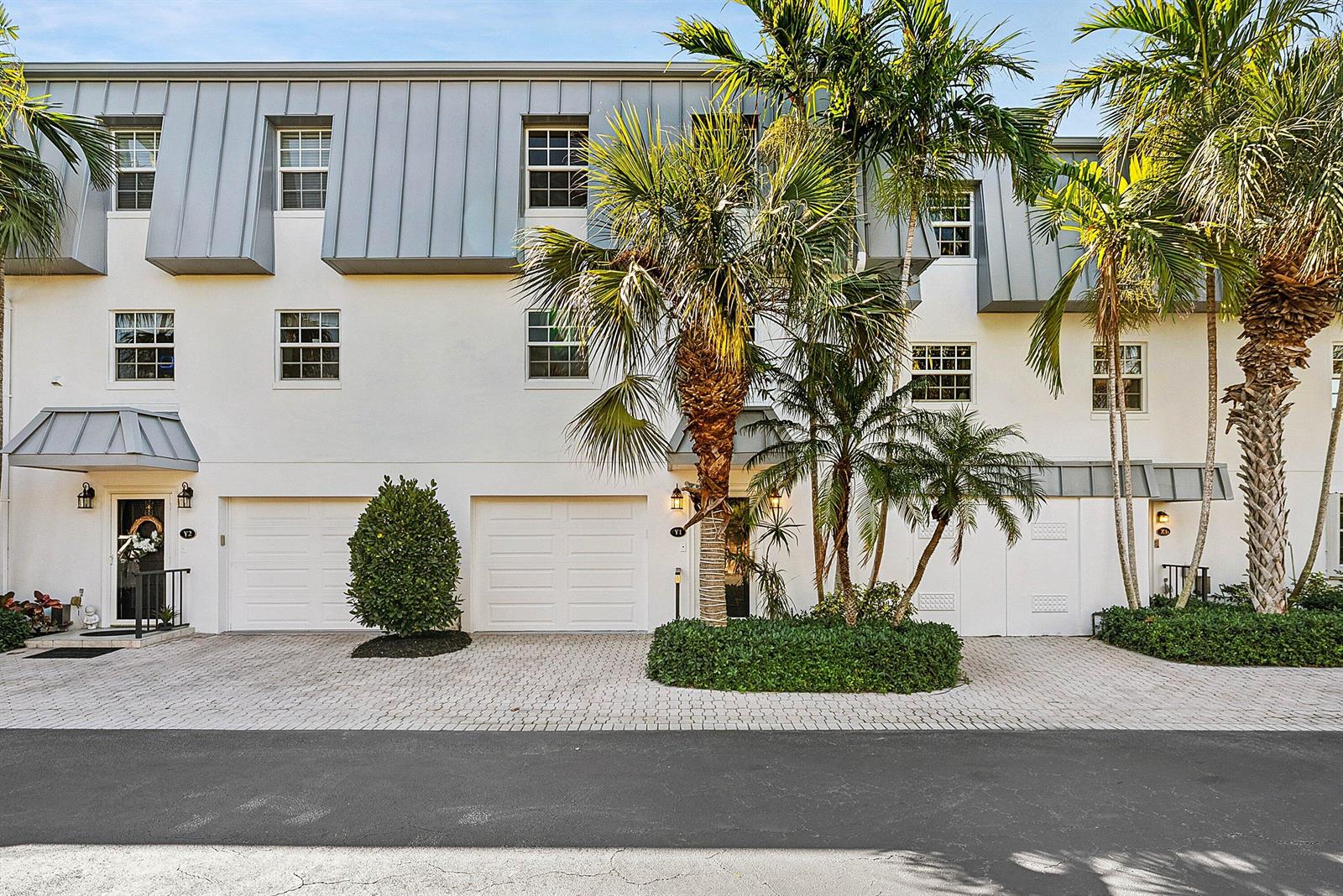 A row of white townhouses with metal mansard roofs, garage doors, and palm trees in front — 2000 S Ocean Boulevard # Y1, Delray Beach FL 33483, DELRAY BEACH, FL