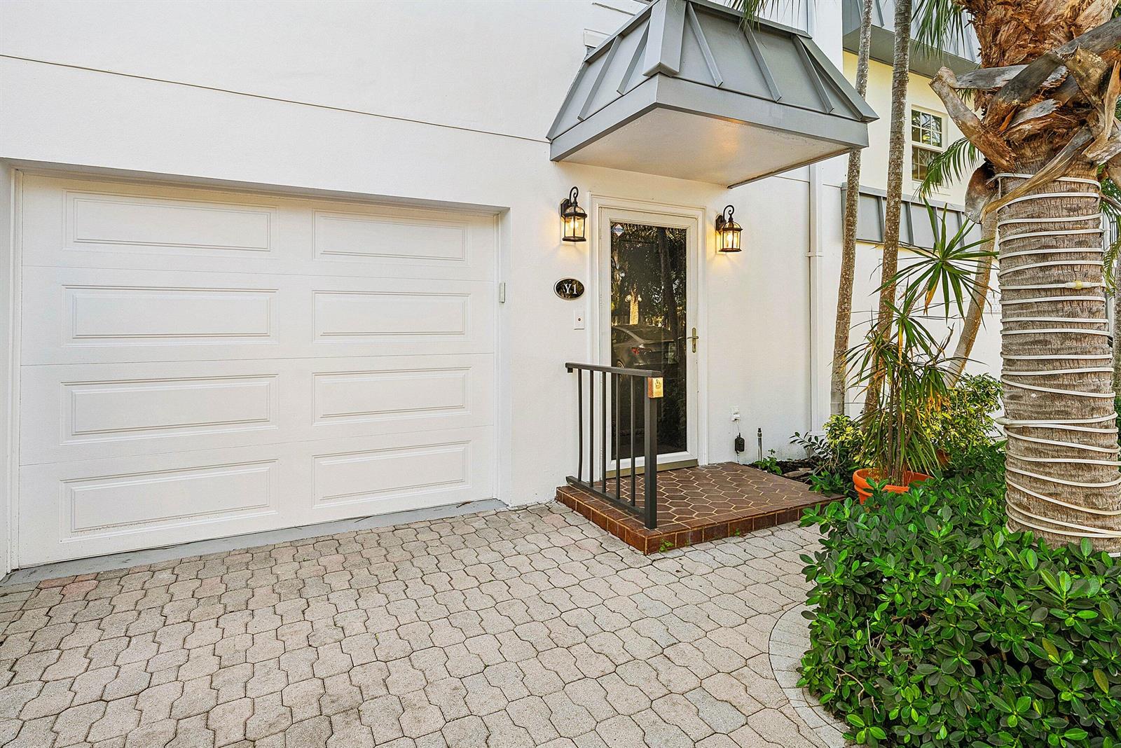A white exterior features a garage door, a front door with a metal awning, and pavers — 2000 S Ocean Boulevard # Y1, Delray Beach FL 33483, DELRAY BEACH, FL