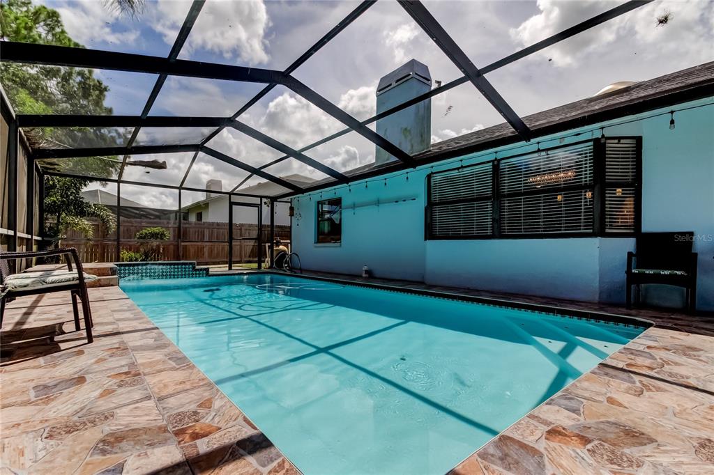 A screened-in swimming pool with a stone patio sits beside a light blue house exterior — 1800 SAGEBRUSH ROAD, PLANT CITY, FL