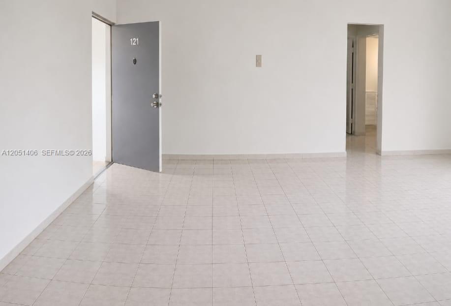 An interior view shows a room with white walls, light-colored tile flooring, and two doorways — 13500 NE 3rd Ct # 121, North Miami FL 33161, NORTH MIAMI, FL