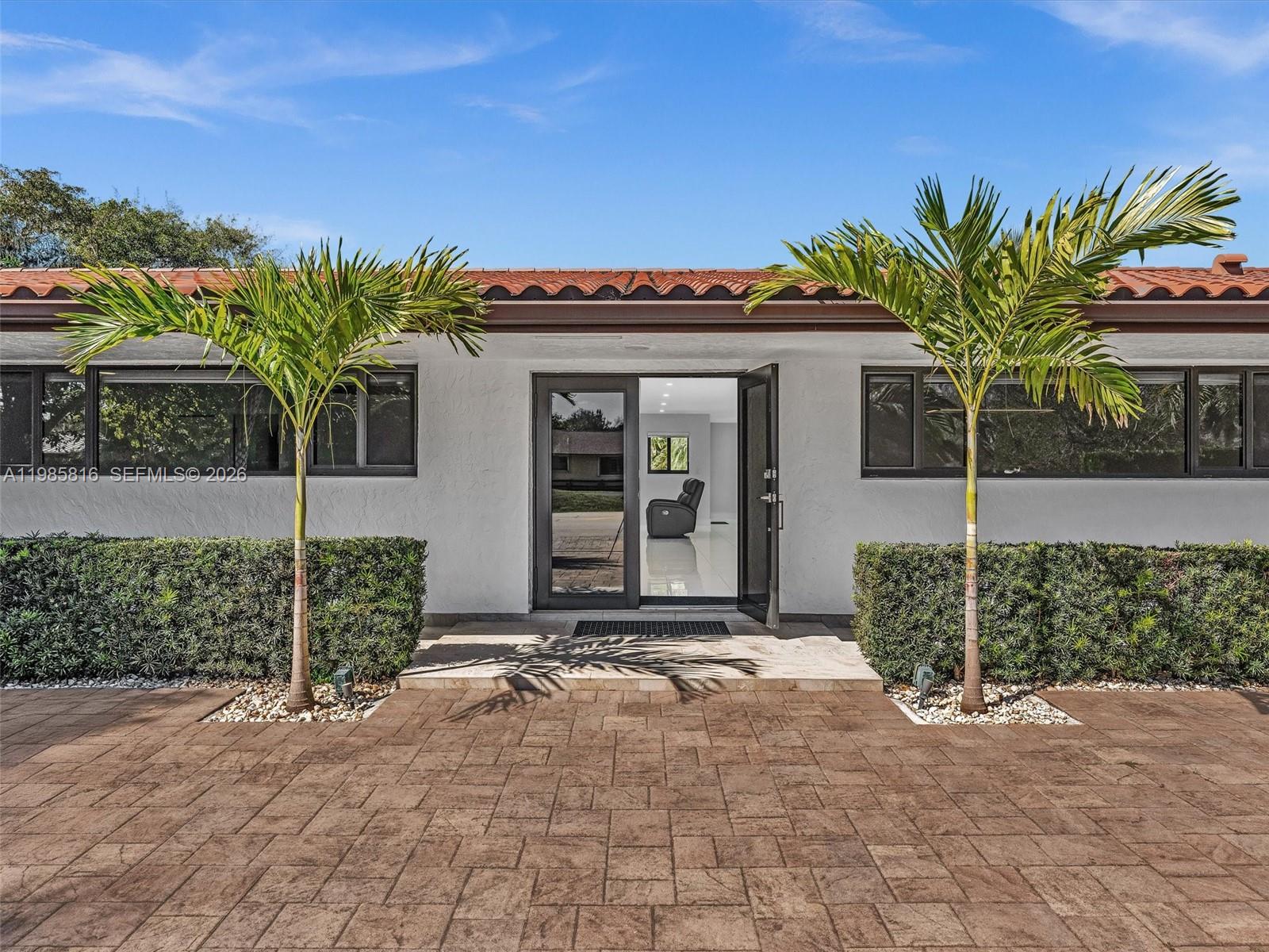 A white house exterior features a tiled patio, two palm trees, and an open doorway — 4501 SW 133rd Ave, Southwest Ranches FL 33330, SOUTHWEST RANCHES, FL