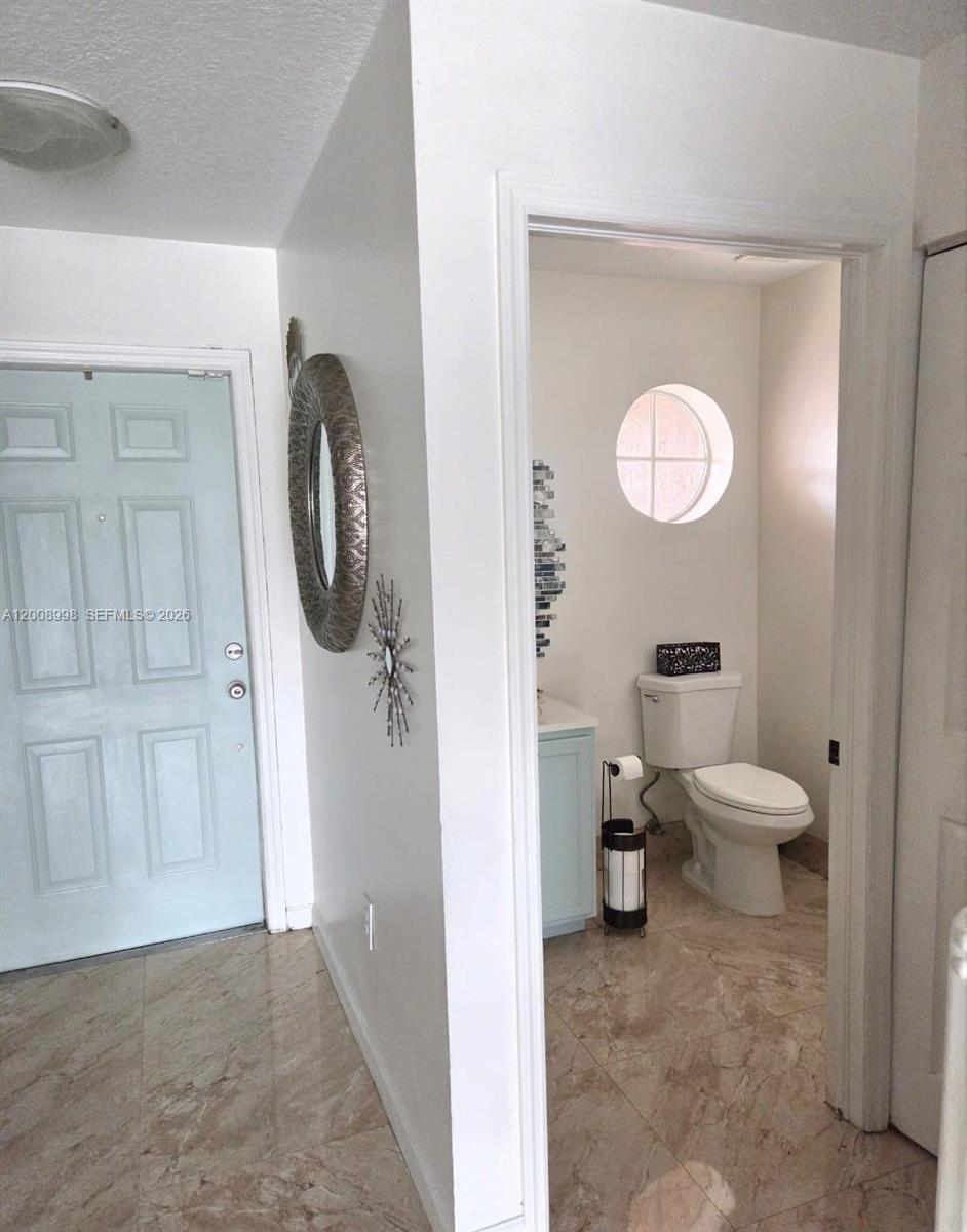 A light blue door opens to a hallway with a bathroom featuring a circular window — 16504 SW 71st Ter, Miami FL 33193, MIAMI, FL