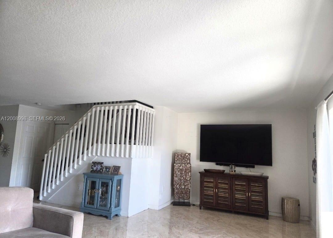 A living room features a staircase with white railings, a television, and tile flooring — 16504 SW 71st Ter, Miami FL 33193, MIAMI, FL