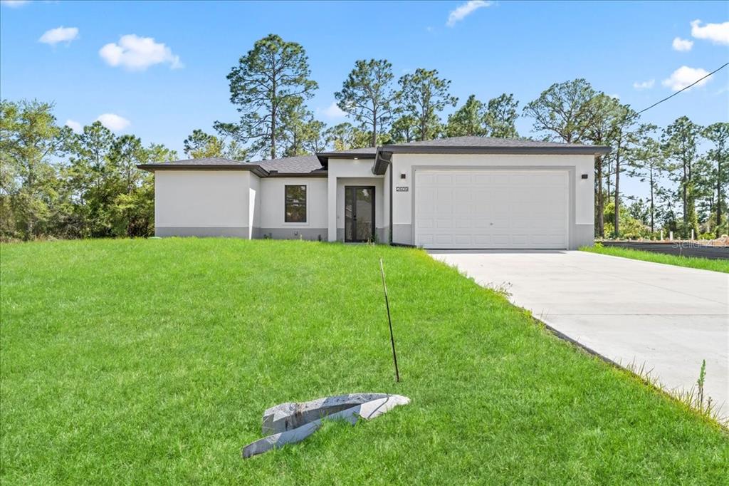 A modern, single-story house with a white exterior, a two-car garage, and a large lawn — 2914 67TH STREET W, LEHIGH ACRES, FL