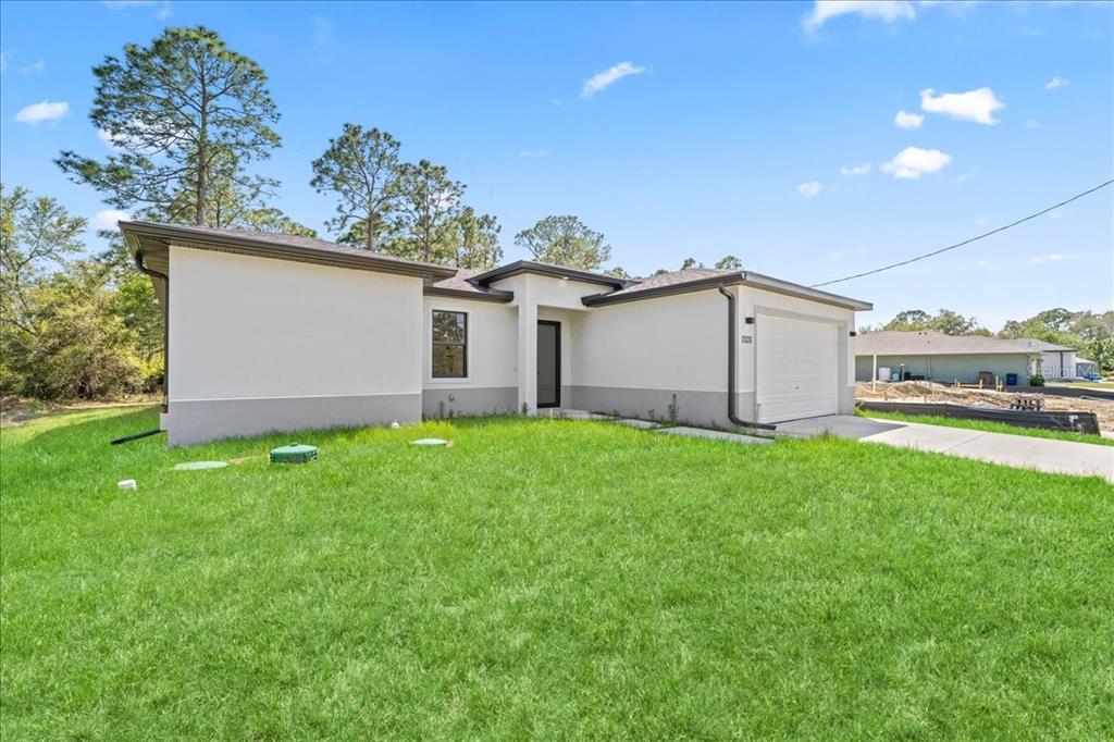 A single-story house with a white stucco exterior, a gray base, and an attached garage — 2914 67TH STREET W, LEHIGH ACRES, FL