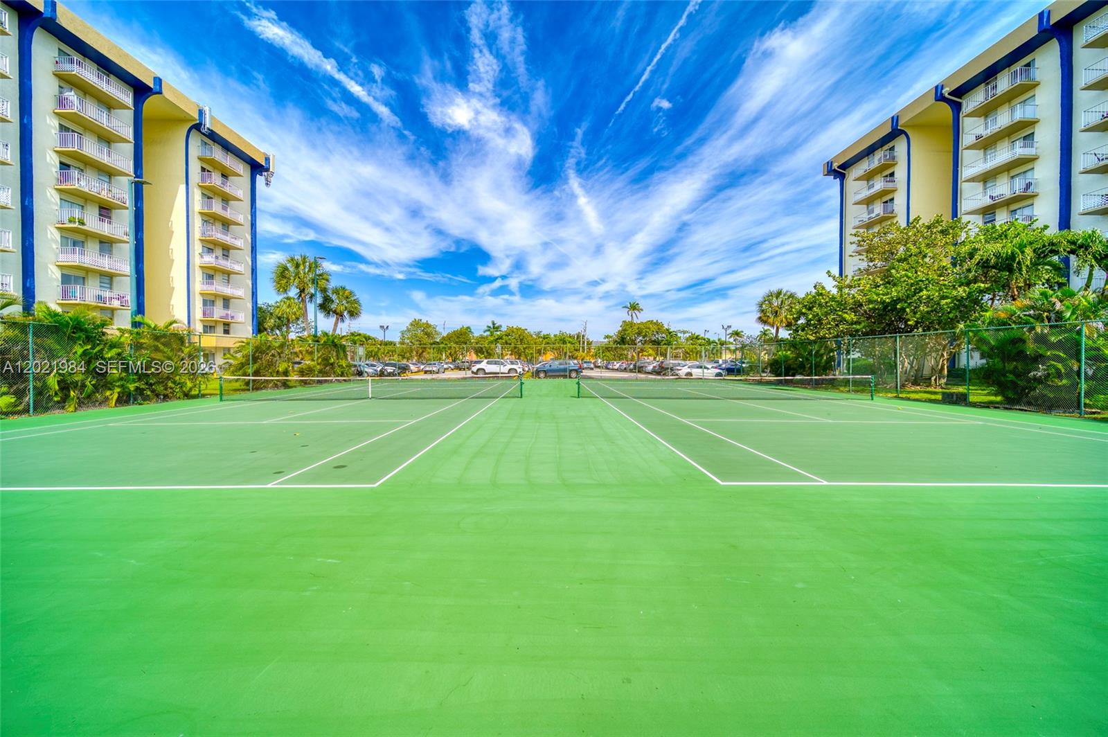 Two tennis courts are situated between two tall apartment buildings under a blue sky — 801 NW 47th Ave # 515W, Miami FL 33126, MIAMI, FL