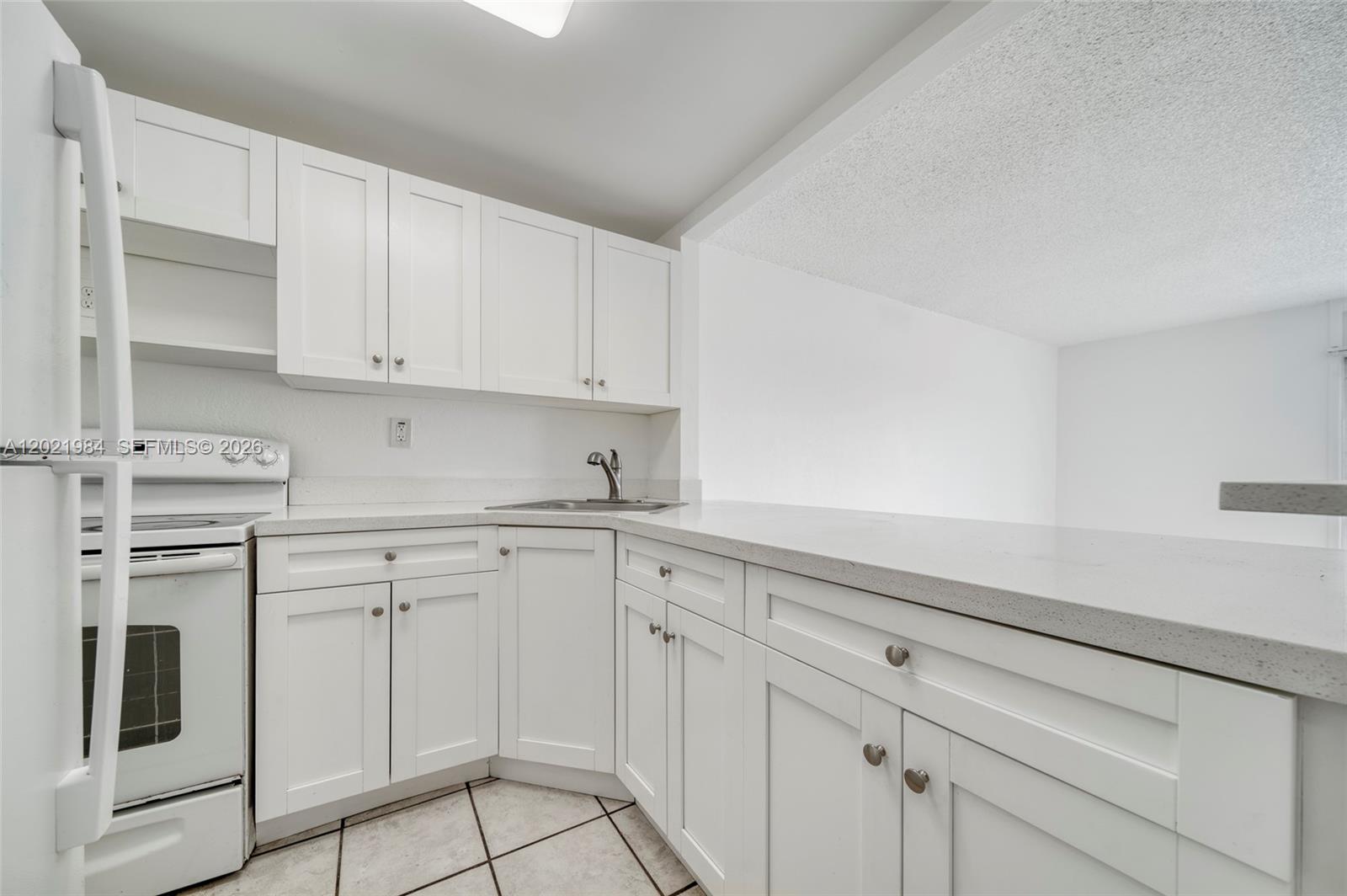 A kitchen features white cabinets, light countertops, and tile flooring — 801 NW 47th Ave # 515W, Miami FL 33126, MIAMI, FL