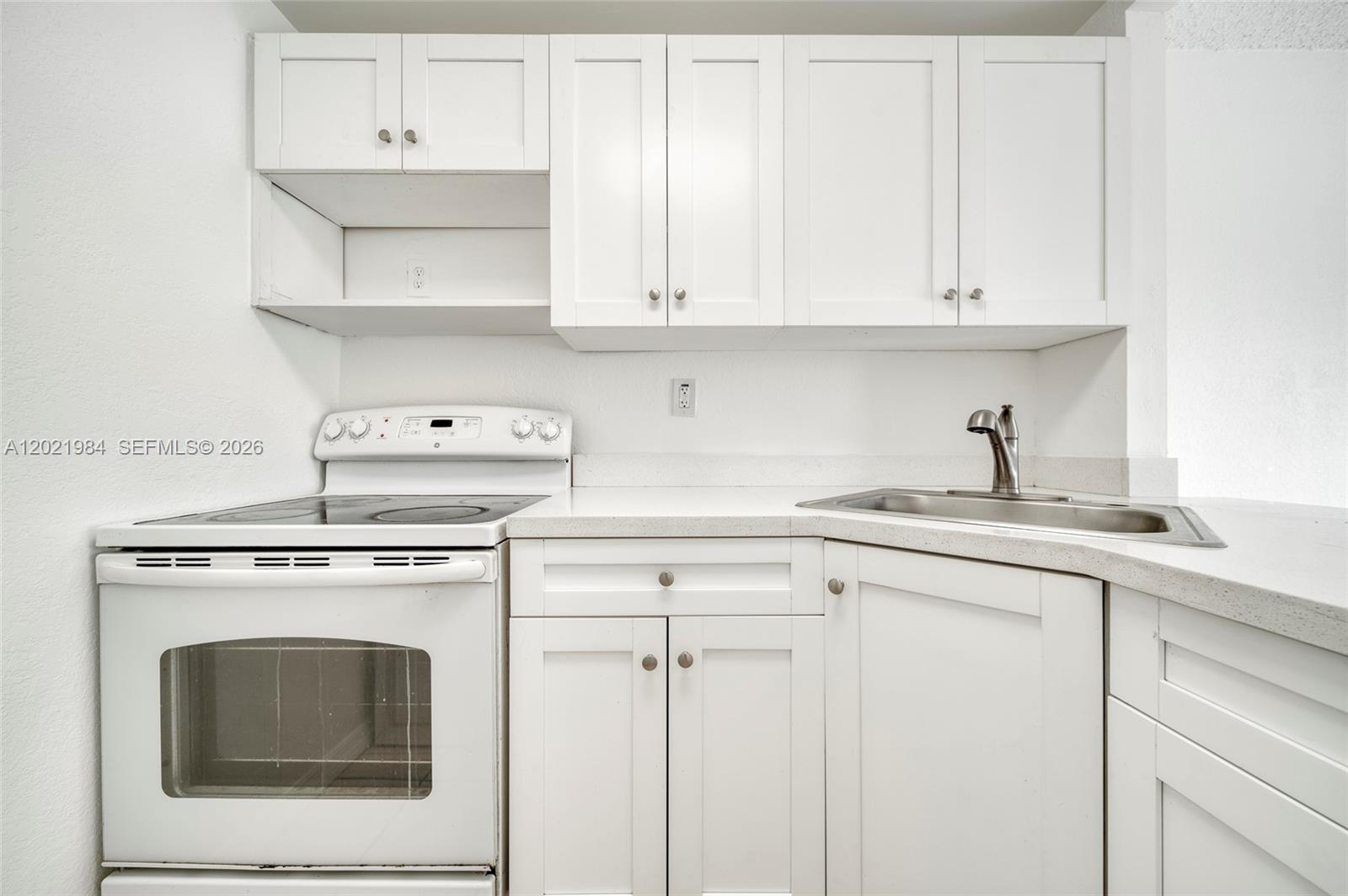 A kitchen features white cabinets, a white electric stove, and a corner stainless steel sink — 801 NW 47th Ave # 515W, Miami FL 33126, MIAMI, FL