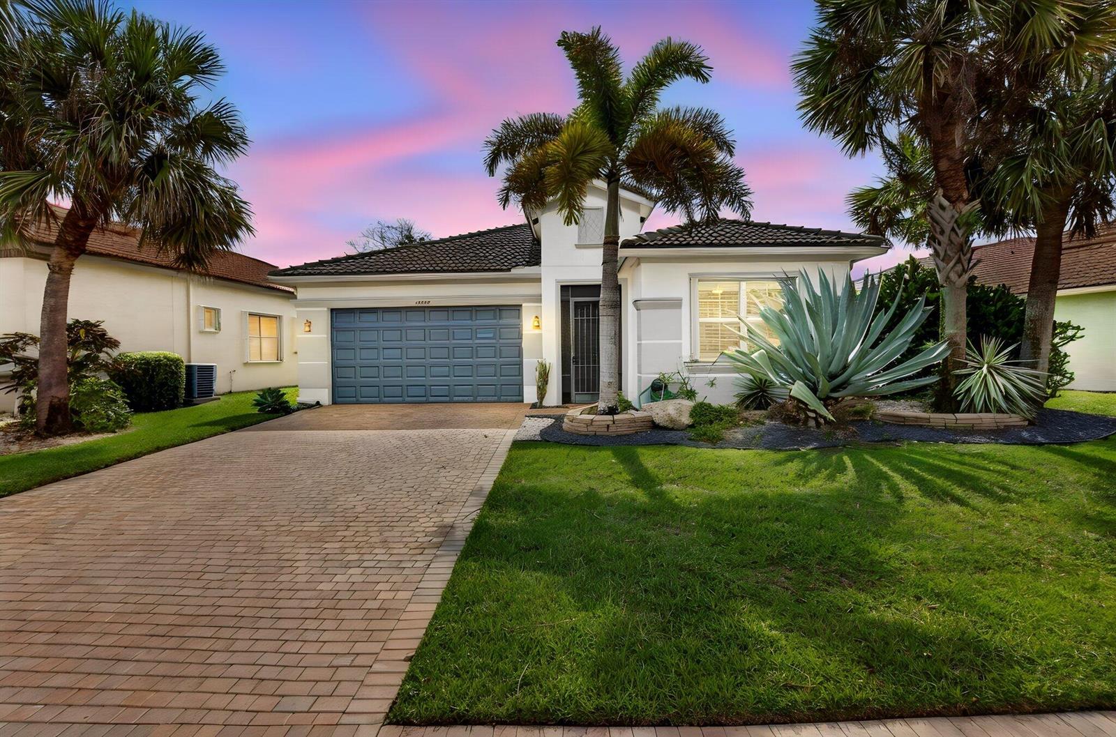 A single-story house with a blue garage door, palm trees, and a brick driveway — 14788 Strand Lane, Delray Beach FL 33446, DELRAY BEACH, FL