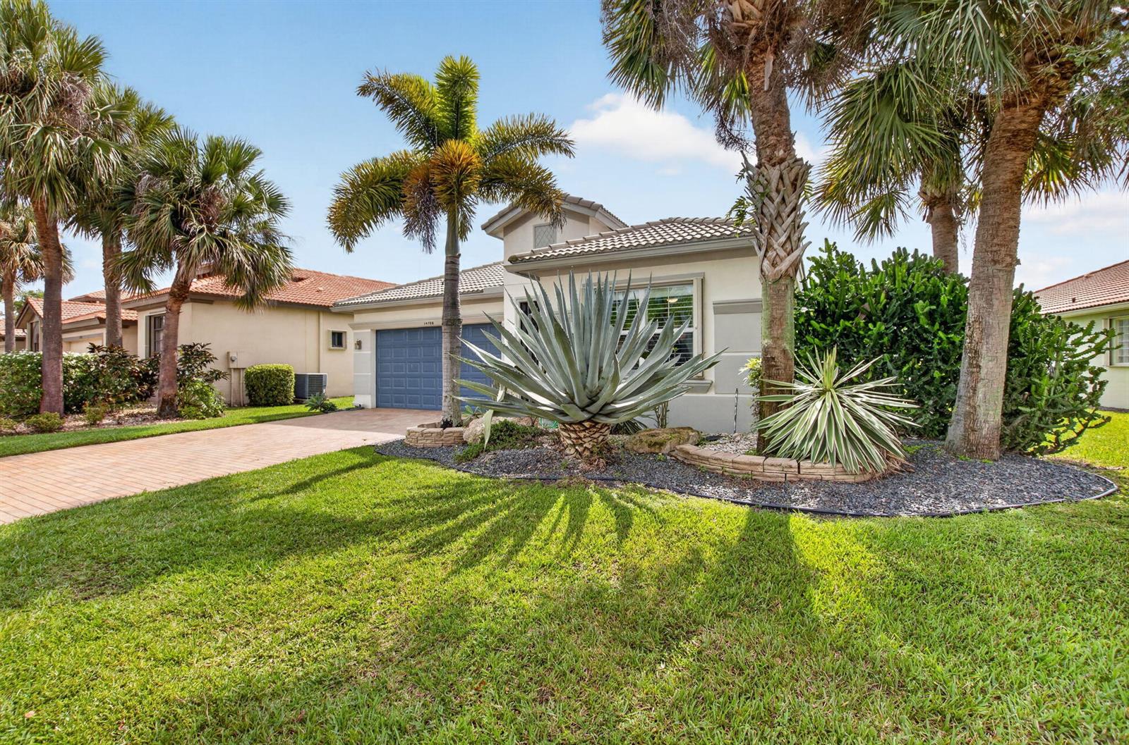 A single-story house with a blue garage door, palm trees, and landscaping in the front — 14788 Strand Lane, Delray Beach FL 33446, DELRAY BEACH, FL