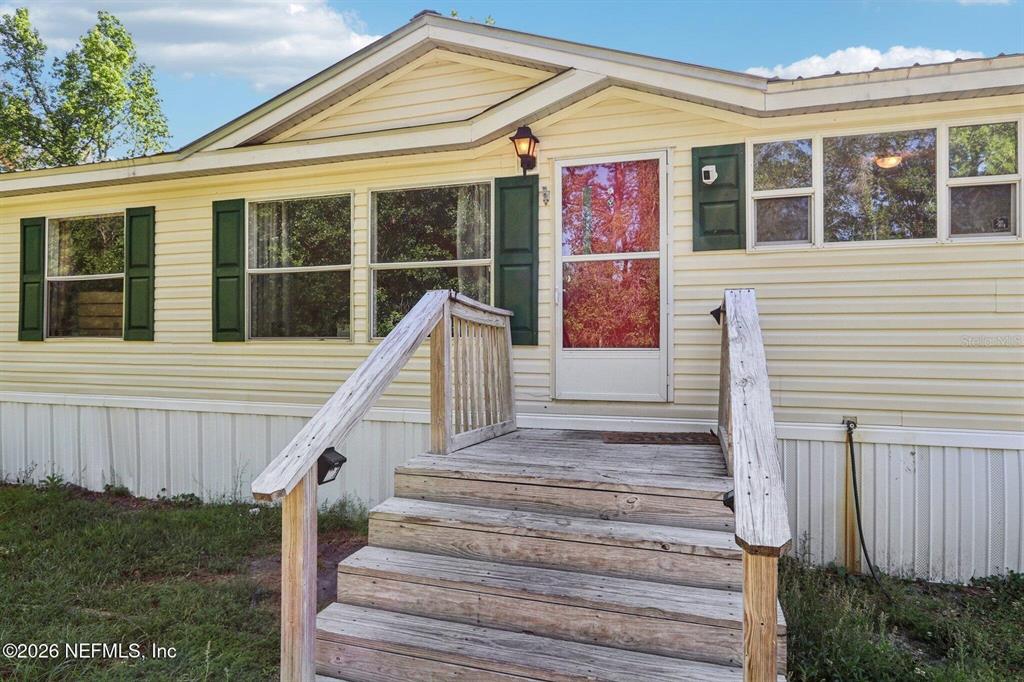 A light yellow manufactured home features a wooden front staircase and dark green shutters — 14070 JOHN WILLIAMS ROAD, SANDERSON, FL