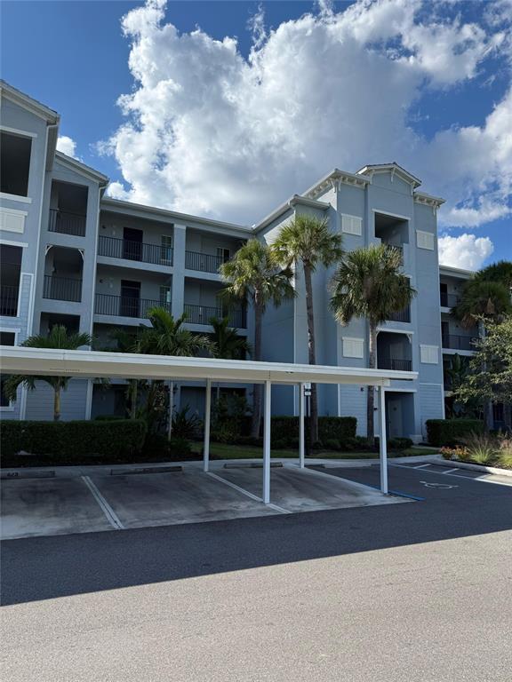 A multi-story apartment building features balconies and a covered parking area with palm trees — 14061 HERITAGE LANDING BOULEVARD UNIT 443, PUNTA GORDA, FL