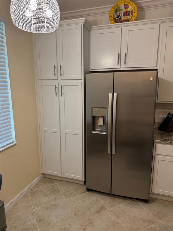 A kitchen features white cabinetry, a stainless steel refrigerator, and light-colored tile flooring — 14061 HERITAGE LANDING BOULEVARD UNIT 443, PUNTA GORDA, FL