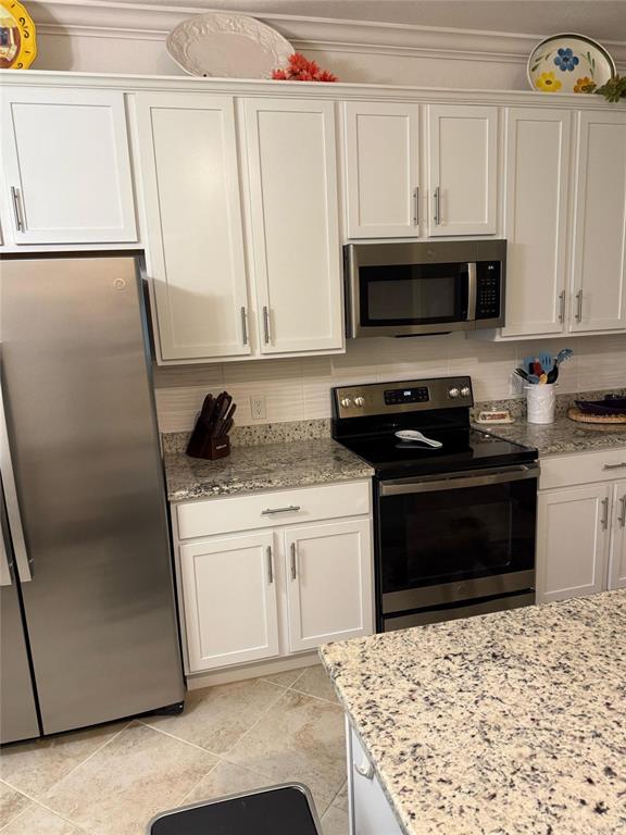 A kitchen features white cabinets, stainless steel appliances, and granite countertops — 14061 HERITAGE LANDING BOULEVARD UNIT 443, PUNTA GORDA, FL