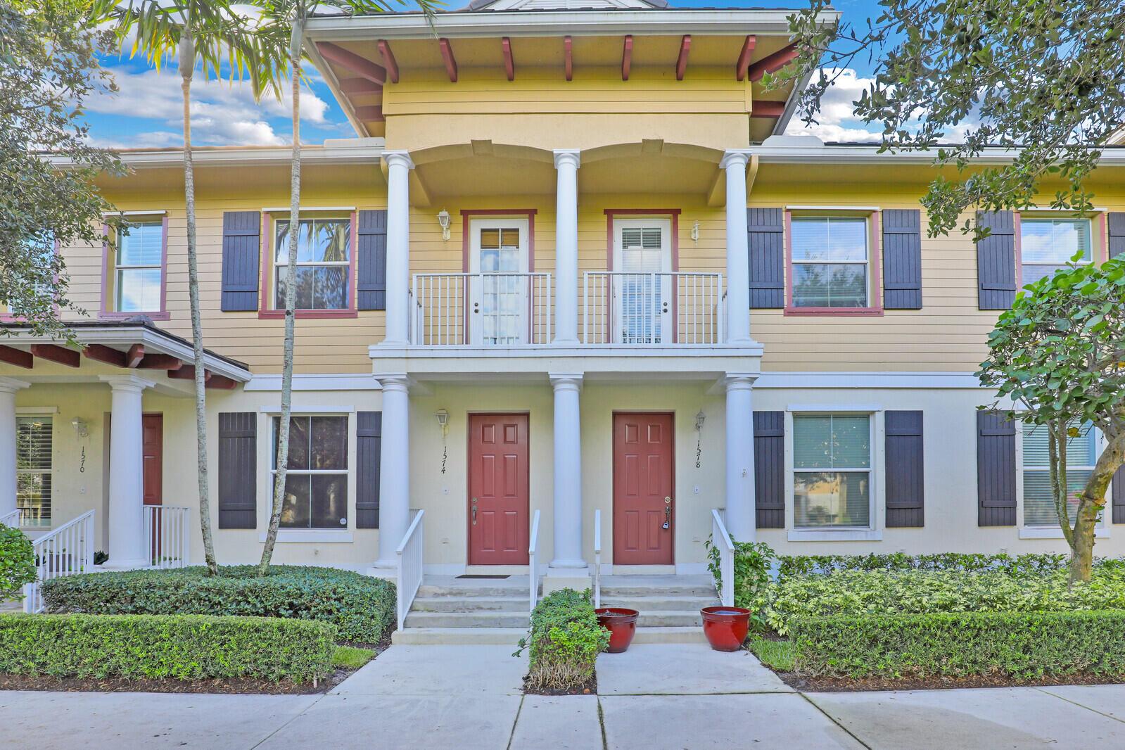 A two-story building exterior features beige siding, red doors, white columns, and small balconies — 1578 Frederick Small Road, Jupiter FL 33458, JUPITER, FL