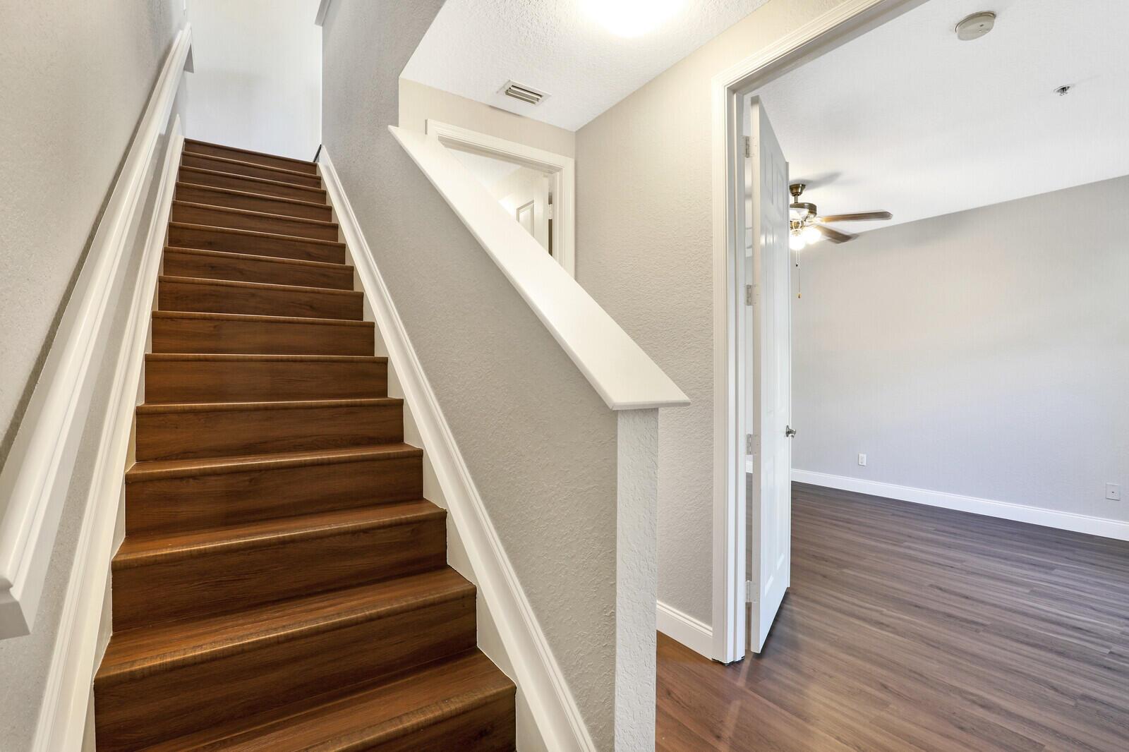 A staircase with wood treads leads upward next to a doorway opening into a room — 1578 Frederick Small Road, Jupiter FL 33458, JUPITER, FL