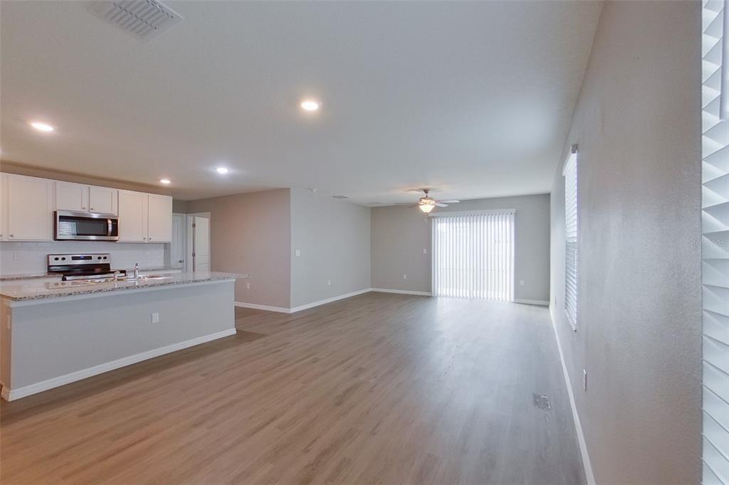 An open-concept kitchen and living area with light wood-look flooring and white cabinets — 8584 SW 43RD TERRACE, OCALA, FL