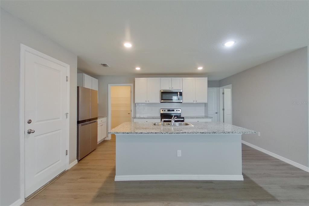 A kitchen features white cabinets, granite countertops, a central island, and stainless steel appliances — 8584 SW 43RD TERRACE, OCALA, FL