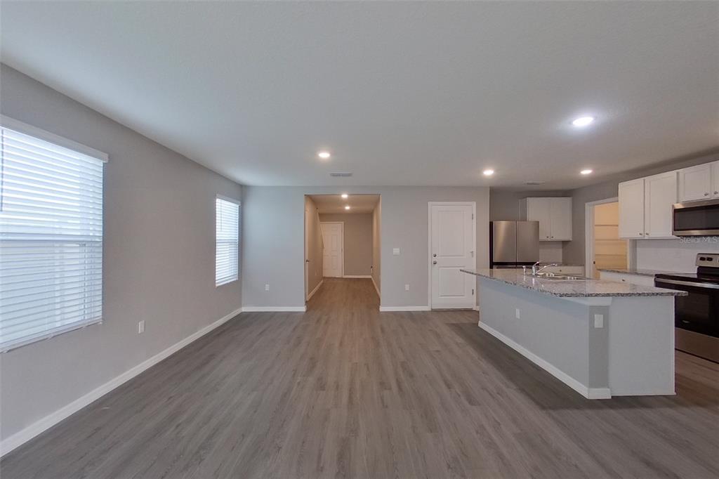 An open-concept kitchen and living area features gray wood-look flooring and white cabinetry — 8584 SW 43RD TERRACE, OCALA, FL