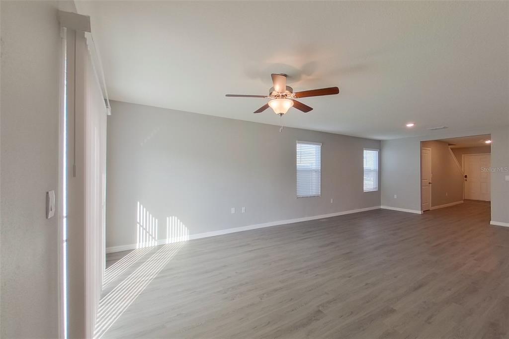 An empty living room features light gray walls, wood-look flooring, and a ceiling fan — 8584 SW 43RD TERRACE, OCALA, FL