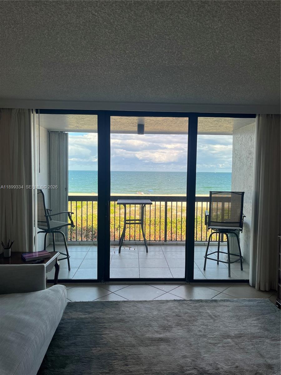A patio with tables, chairs, and palm trees overlooks a sandy beach and the ocean — 510 N Ocean Blvd # 211, Pompano Beach FL 33062, POMPANO BEACH, FL
