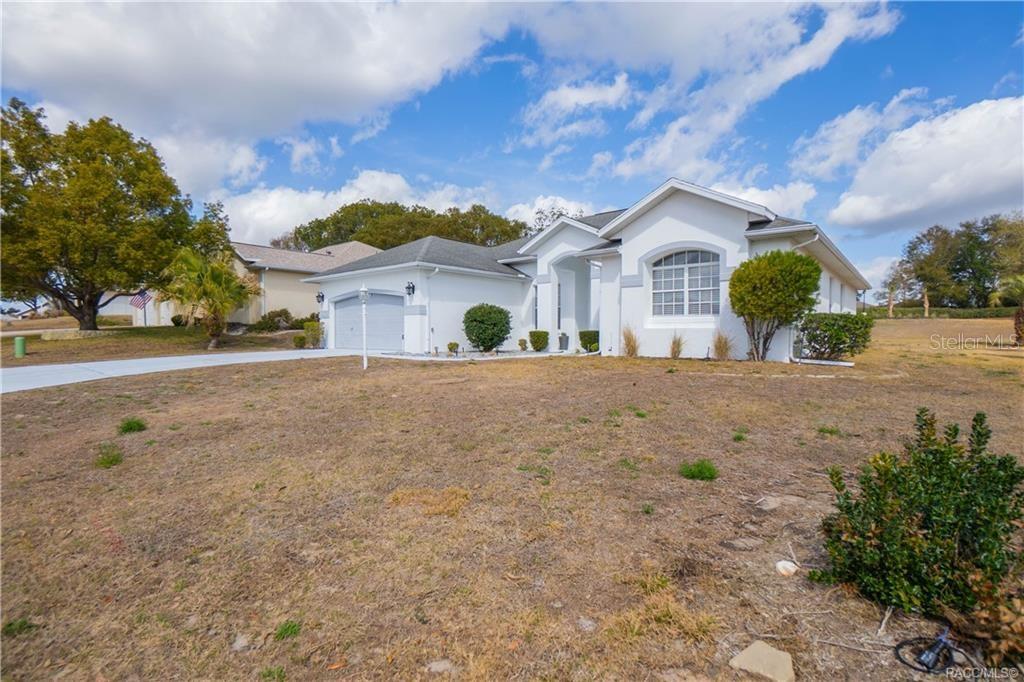 A single-story white house with a two-car garage and a dry, grassy front yard — 389 W HILLMOOR LANE, BEVERLY HILLS, FL