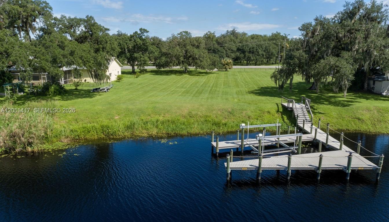 An aerial view shows a grassy backyard leading to a wooden dock on a canal — 395 Old County Road 78, La Belle FL 33935, LA BELLE, FL