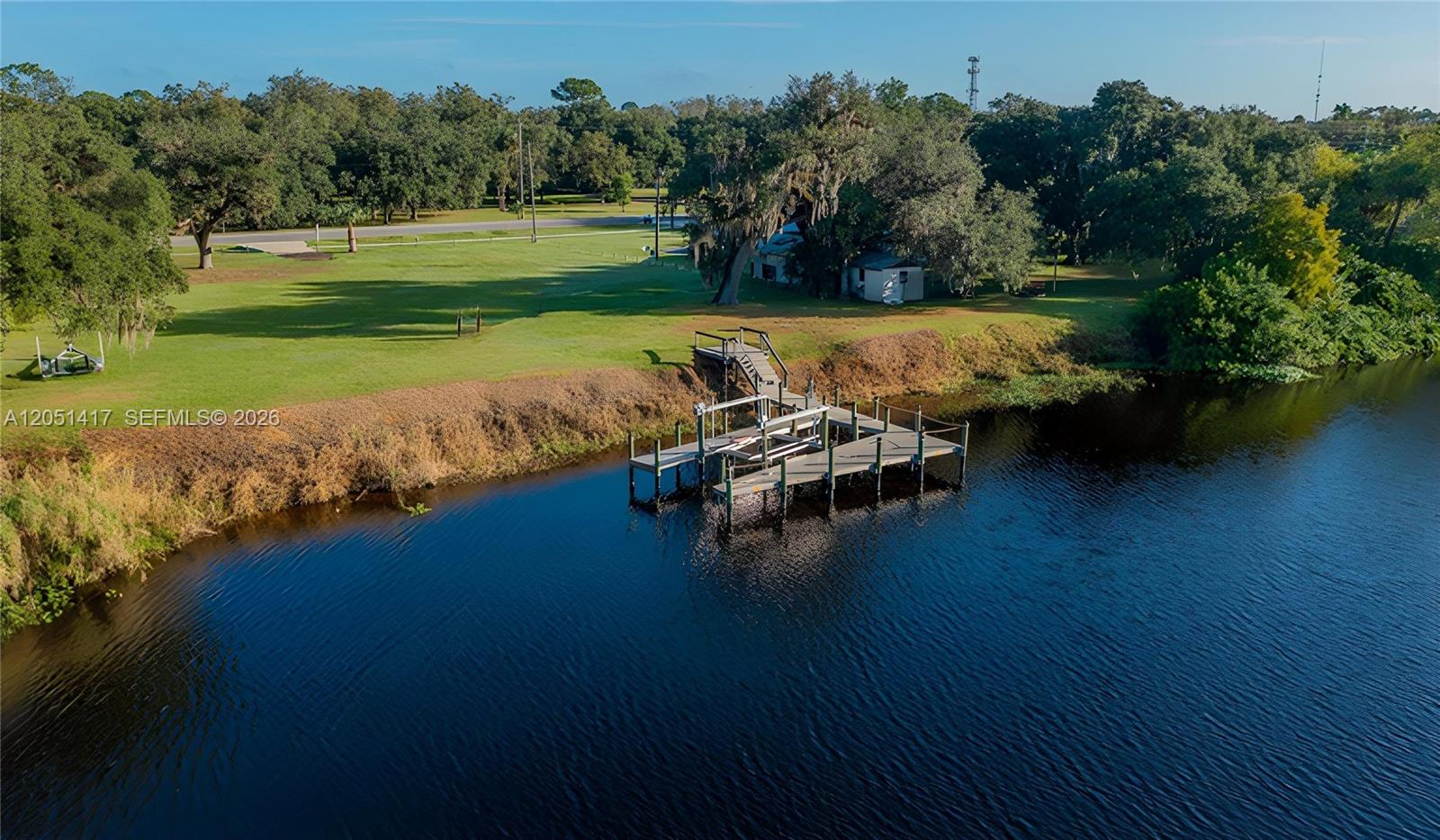 An aerial view shows a wooden dock extending into a river from a grassy lawn — 395 Old County Road 78, La Belle FL 33935, LA BELLE, FL