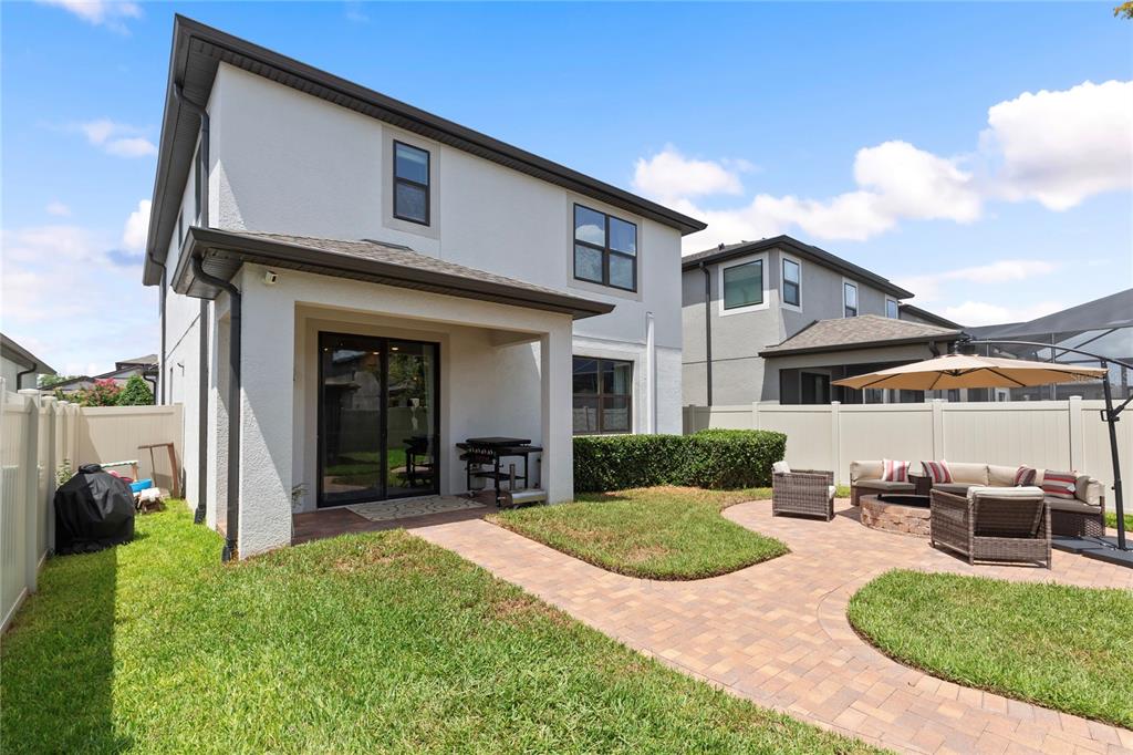 A two-story house exterior features a covered patio, brick paver walkway, and a fenced backyard — 19364 BREYNIA DRIVE, LUTZ, FL