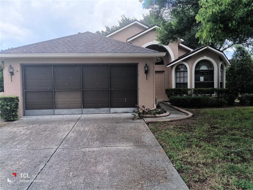 A tan single-story house features a three-panel garage door and an arched entryway — 13652 PIMBERTON DRIVE, HUDSON, FL