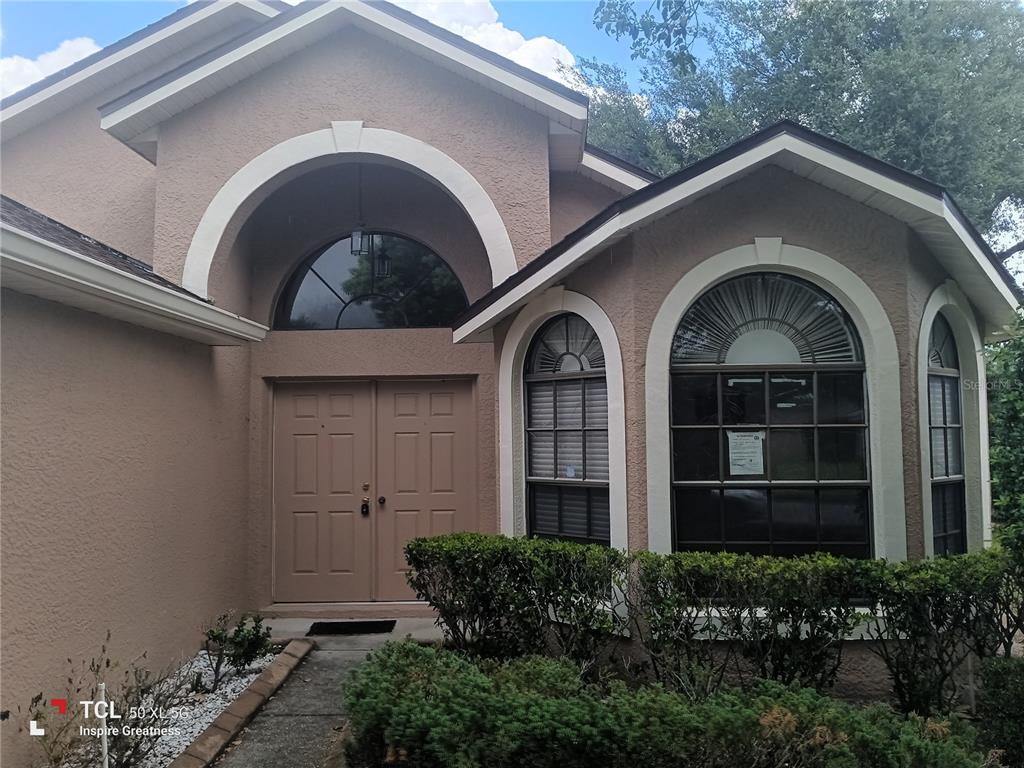 The exterior of a tan house features a double front door and arched windows — 13652 PIMBERTON DRIVE, HUDSON, FL