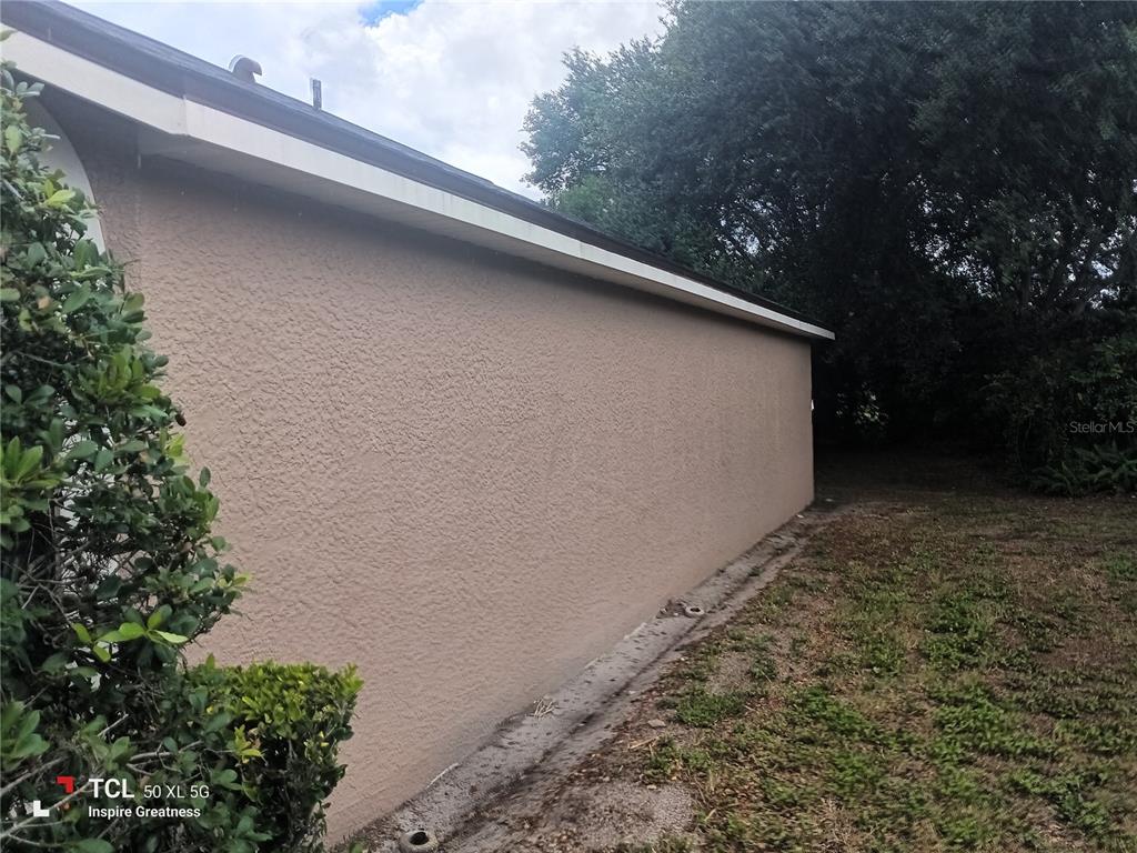 A side view of a house with a beige stucco wall and a white soffit — 13652 PIMBERTON DRIVE, HUDSON, FL