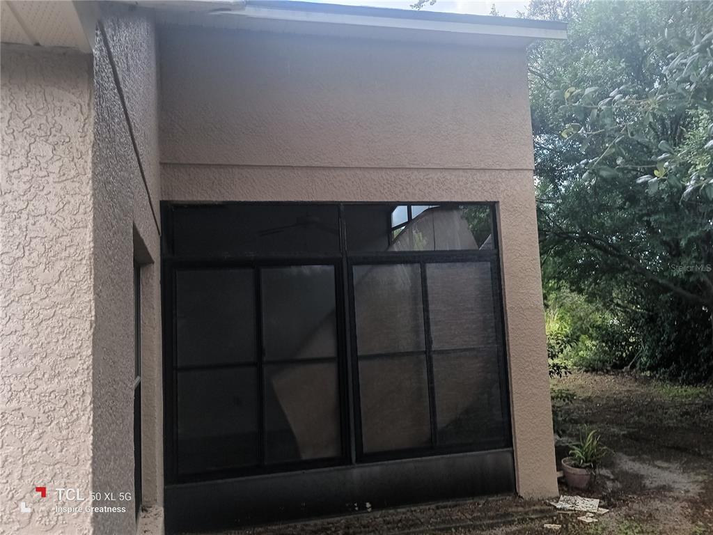 An exterior view of a stucco home featuring a screened-in porch with sliding glass windows — 13652 PIMBERTON DRIVE, HUDSON, FL