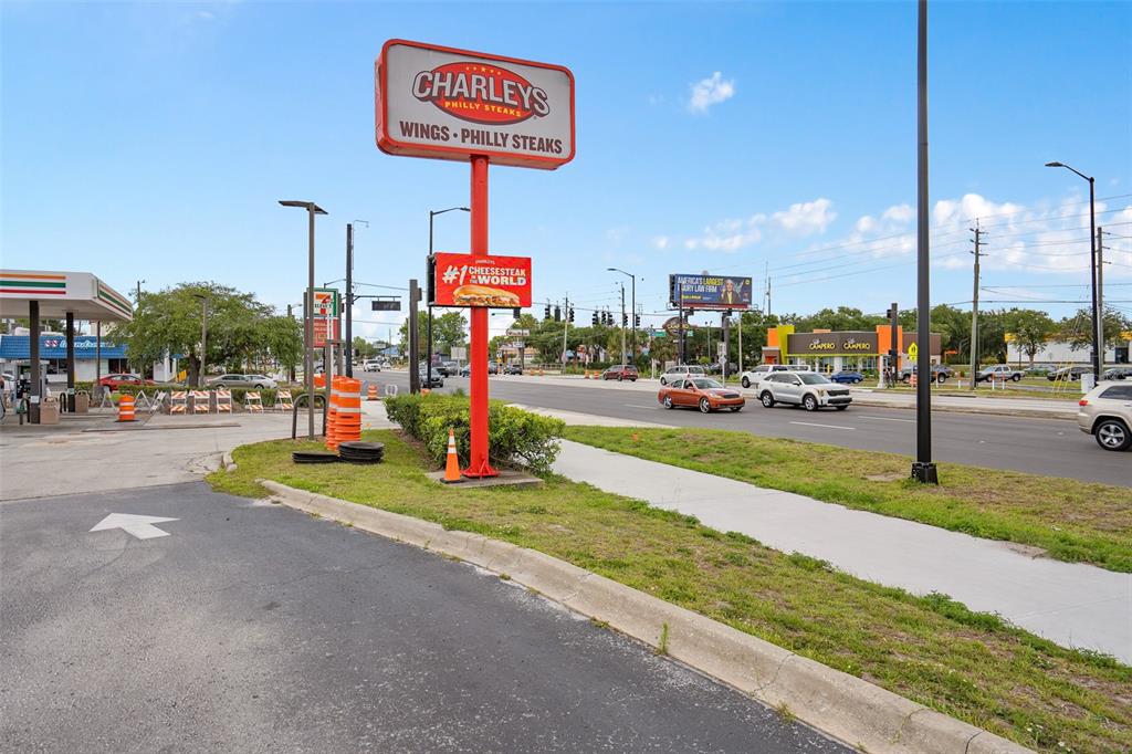 A Charleys Philly Steaks sign stands near a 7-Eleven and a busy road — 3250 W VINE STREET, KISSIMMEE, FL