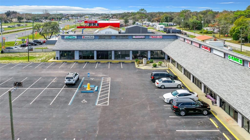 An aerial view of a commercial strip mall with a parking lot and several businesses — 15215 US HIGHWAY 19 UNIT A, HUDSON, FL