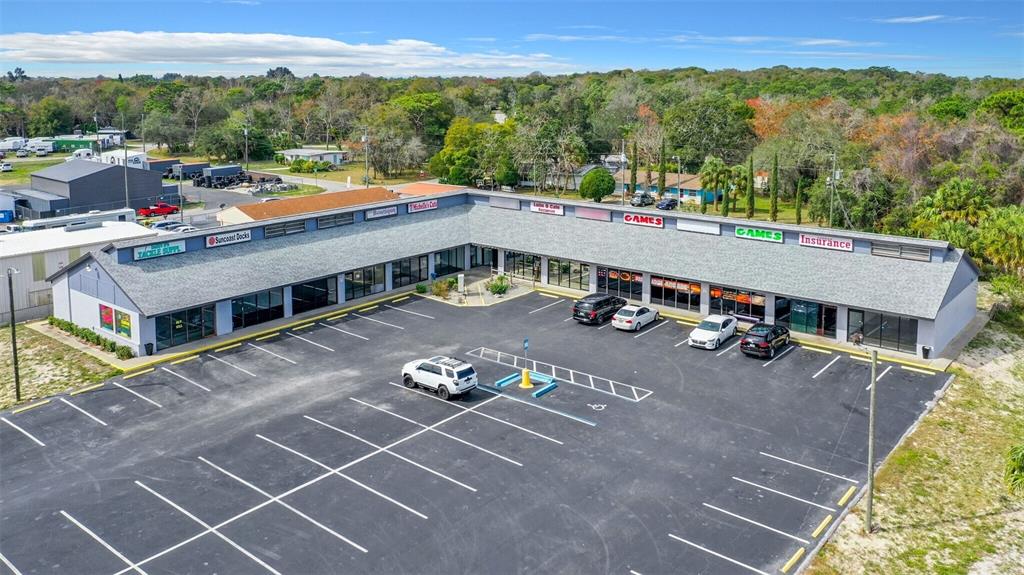 An aerial view of a single-story commercial strip mall with a large asphalt parking lot — 15215 US HIGHWAY 19 UNIT A, HUDSON, FL